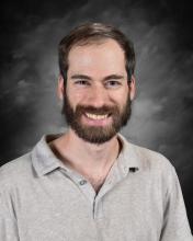 Smiling man wearing light colored shirt.